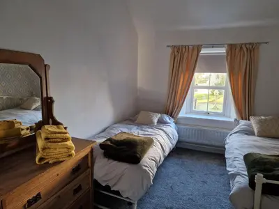 a bedroom with two beds and a dresser and a window at Victoria Cottage in Whitrigg