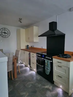 a kitchen with a black stove top oven next to a table at Victoria Cottage in Whitrigg