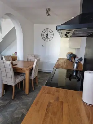 a kitchen with a wooden table and a dining room at Victoria Cottage in Whitrigg