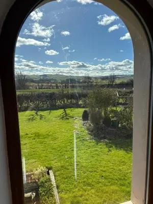 an arched window looking out at a green field at Kingate Cottage in Aspatria