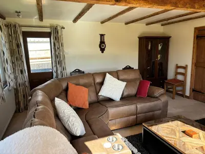 a living room with a brown leather couch at Kingate Cottage in Aspatria