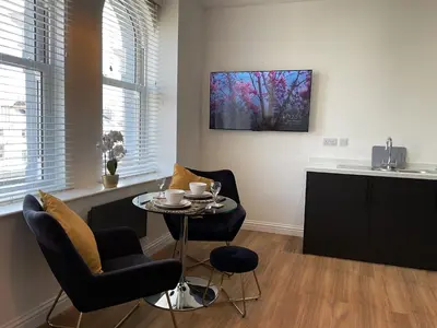 a living room with a table and chairs and a kitchen at 8 Clifton Terrace in Douglas