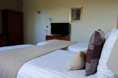 a hotel room with two beds and a flat screen tv at Highgrove House Hotel in Loans