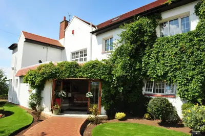 a white house with an ivy covered building at Highgrove House Hotel in Loans