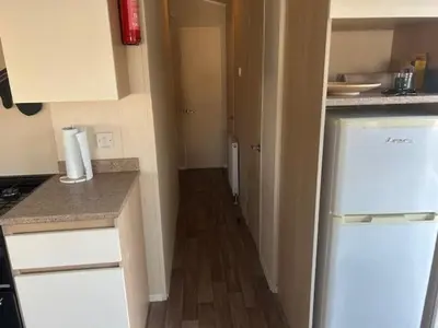 a small kitchen with a refrigerator and a hallway at Seabreeze Retreat in Port Carlisle