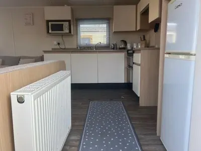 a kitchen with white cabinets and a blue and white rug at Seabreeze Retreat in Port Carlisle