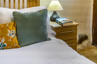 a bed with a green pillow and a lamp on a night stand at 3 Bed in Waberthwaite oc-d31079 in Waberthwaite