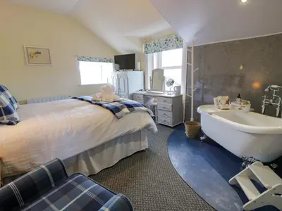 a bedroom with a bed and a tub and a sink at The Lamphouse in Stranraer