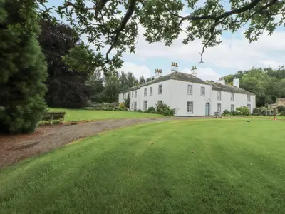 a large white house with a large green yard at Westward Park in Wigton