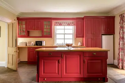 a kitchen with red cabinets and a window at Auchengashell in Kirkcudbright