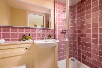 a pink tiled bathroom with a sink and a shower at Auchengashell in Kirkcudbright