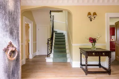 a hallway with stairs and a table with flowers on it at Auchengashell in Kirkcudbright