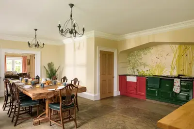 a kitchen with a wooden table and red cabinets at Auchengashell in Kirkcudbright