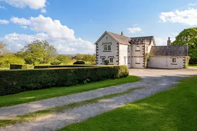 an old house with a driveway in front of it at Auchengashell in Kirkcudbright