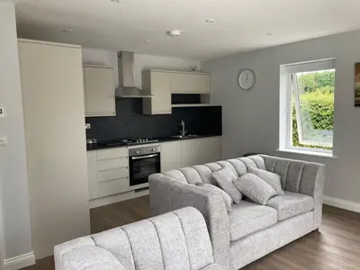 a living room with a couch and a kitchen at Orchard Cottage At Gretna in Gretna