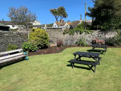 two picnic tables in a yard with a stone wall at The Harbour House Sea Front Hotel in Portpatrick