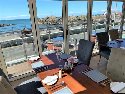 a dining room with a table with a view of the ocean at The Harbour House Sea Front Hotel in Portpatrick