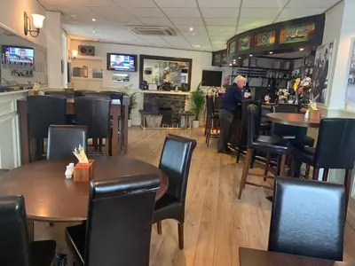 a man standing in a restaurant with tables and chairs at The Harbour House Sea Front Hotel in Portpatrick
