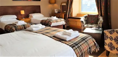 a hotel room with two beds and a chair at The Harbour House Sea Front Hotel in Portpatrick