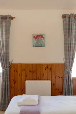 a bedroom with a bed with curtains and a picture at Holiday Home Doonans Cottage by Interhome in Straiton