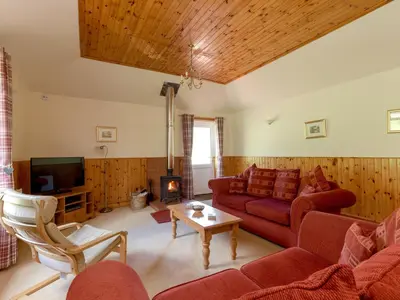 a living room with red couches and a tv at Holiday Home Doonans Cottage by Interhome in Straiton
