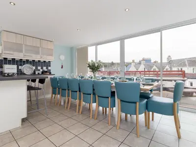 a dining room with a table and blue chairs at Holiday Home The Knowe by Interhome in Portpatrick