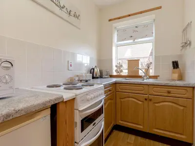 a kitchen with a white stove top oven next to a window at Holiday Home Foxglove cottage by Interhome in Straiton