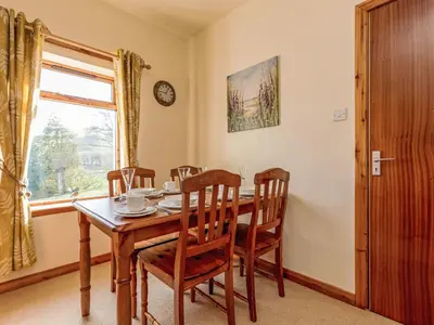 a dining room with a table and chairs and a window at Holiday Home Foxglove cottage by Interhome in Straiton