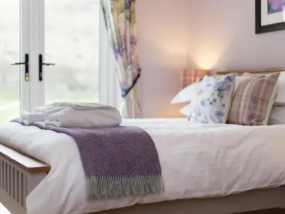 a bedroom with a bed with a purple blanket on it at Holiday Home Balbeg Cottage by Interhome in Straiton