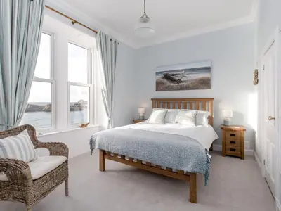 a bedroom with a bed and a chair and a window at Holiday Home Portpatrick House by Interhome in Portpatrick