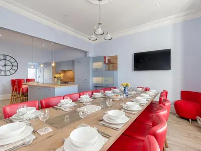 a large dining room with a long table and red chairs at Holiday Home Portpatrick House by Interhome in Portpatrick