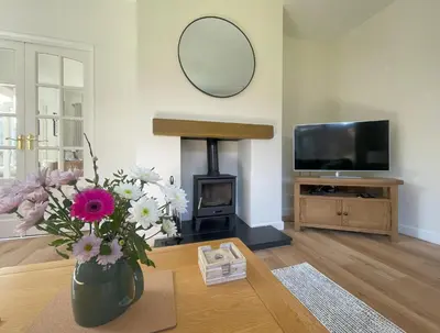 a living room with a fireplace and a vase of flowers at Fern Cottage in Portinscale