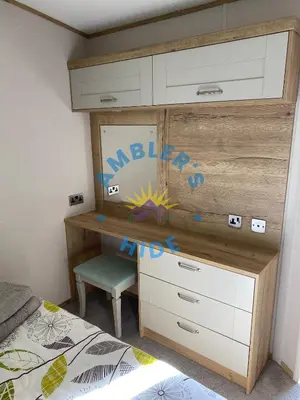 a bedroom with a dresser and a desk with a bed at Amblers Hide, Brigham, Cockermouth, Cumbria in Cockermouth