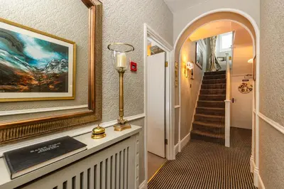 a hallway with a staircase with a painting and a lamp at Raise View House in Ambleside