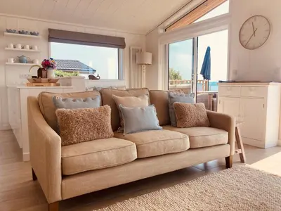 a couch in a living room with a clock on the wall at The Moorings in Girthon