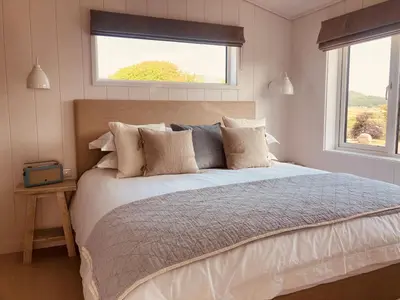 a bedroom with a large bed and two windows at The Moorings in Girthon