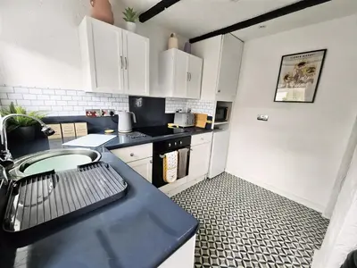 a kitchen with white cabinets and a black counter top at Leaf Tree Cottage, close to Coast, Lakes and Fells in Workington