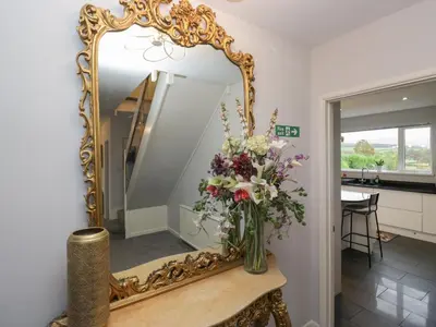 a mirror on a table with a vase of flowers at Eildon Lodge in Seascale