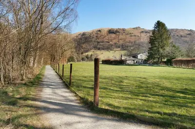 a fence next to a field with a house at Heron View Cottage in Grasmere