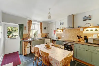 a kitchen with a table and a dining room at Heron View Cottage in Grasmere