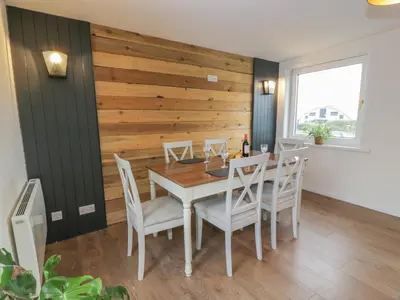 a dining room with a wooden wall and a table and chairs at Swallow Cottage in Dumfries