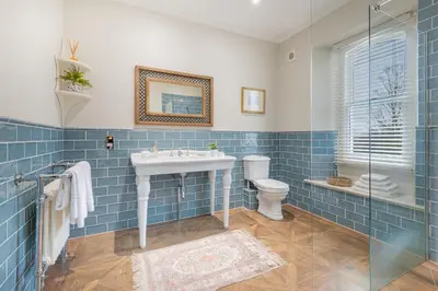 a blue tiled bathroom with a sink and a toilet at Huntingstile South in Ambleside