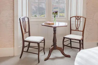 two chairs and a table with a vase of flowers at Huntingstile South in Ambleside