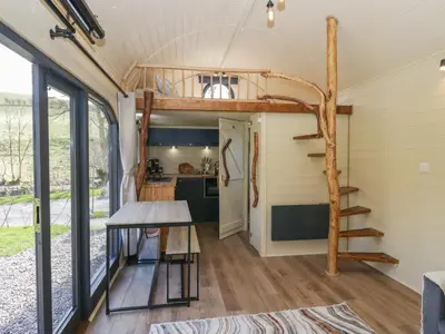 a tiny house with a loft bed and a kitchen at Longlands Lodge in Wigton