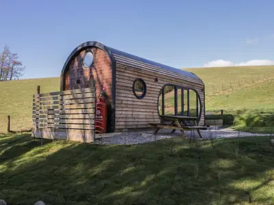 a small shed with a bench in a field at Binsey Lodge in Wigton