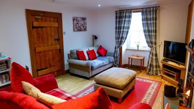 a living room with a red couch and a chair at 9 Millburn Street in Kirkcudbright