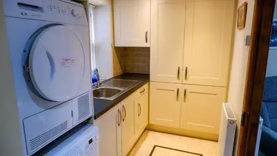 a small kitchen with a washing machine and a sink at 9 Millburn Street in Kirkcudbright