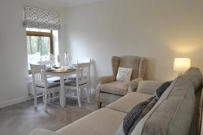 a living room with a couch and a table and chairs at The Tranquil Orchard in Dumfries