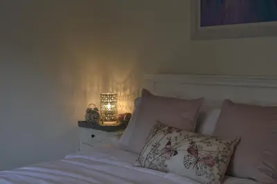 a bedroom with a bed with a lamp on a night stand at The Tranquil Orchard in Dumfries
