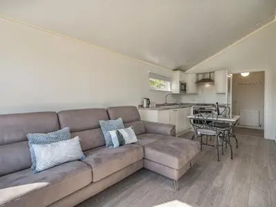 a living room with a couch and a kitchen at The Tranquil Orchard in Dumfries